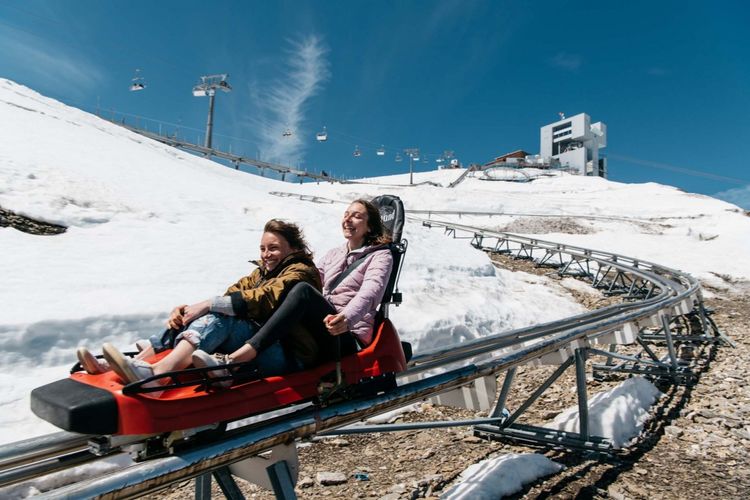 Tempat wisata di Swiss - Dua orang wisatawan sedang menaiki Alpine Coaster menggunakan toboggan di Glacier 3000.