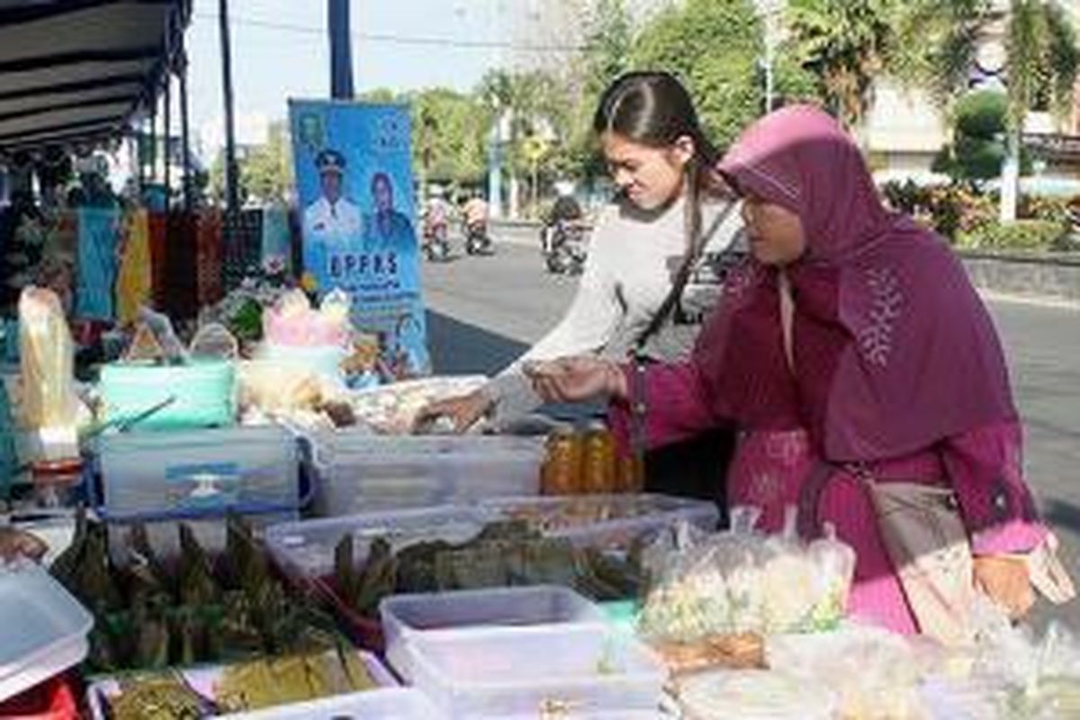 Pengunjung membeli makanan kecil yang dijajakan ibu-ibu pengurus Pembinaan Kesejahteraan Keluarga (PKK) di pasar Ramadhan di alun-alun Kota Madiun, Jawa Timur, Senin (29/6). Kegiatan yang digelar di selatan alun-alun Kota Madiun ini merupakan salah satu sarana promosi produk usaha mikro, kecil, dan menengah.