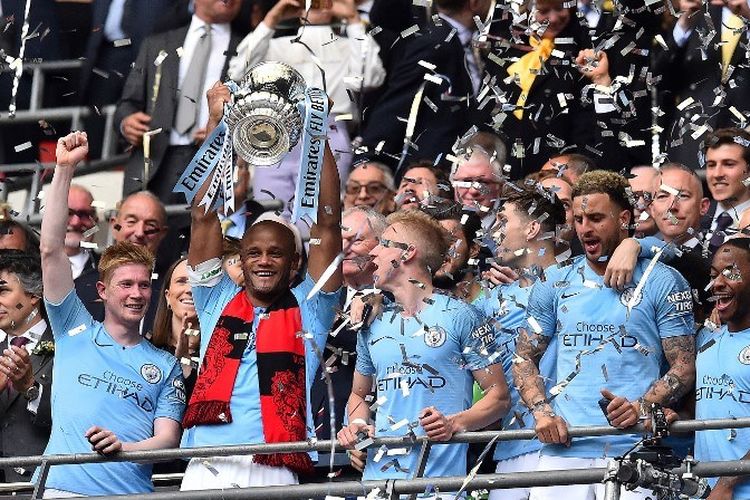 Vincent Kompany mengangkat trofi Piala FA seusai Manchester City menang telak atas Watford pada laga final di Stadion Wembley, 18 Mei 2019. 