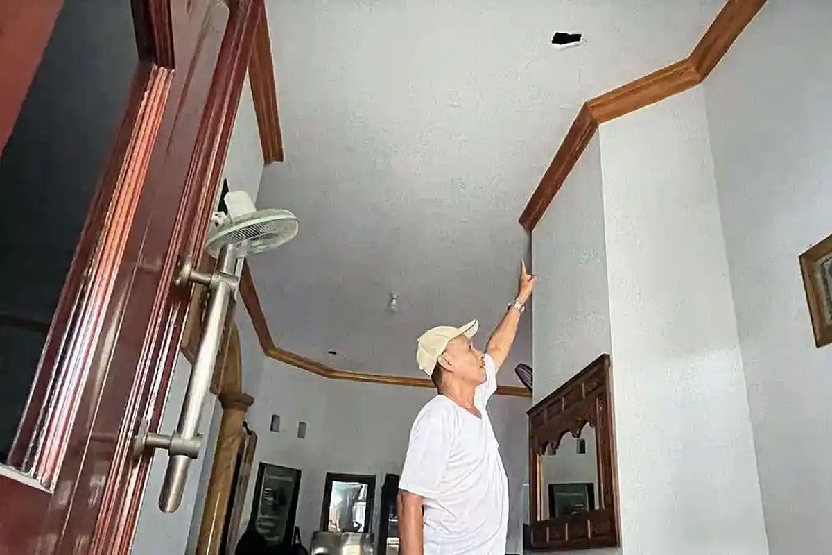 RUSAK - Muhammad Nur Kholis, warga Perumahan Wedoro Regency di Kecamatan Waru, Kabupaten Sidoarjo, Jawa Timur, Selasa (7/4/2026),, saat menunjukkan plafon ruang tamunya rusak akibat serpihan besi yang terlempar 1 km dari ledakan yang terjadi di pabrik PT Great Wall Steel (GWS). Nur Kholis sempat merekam sesaat setelah kejadian.