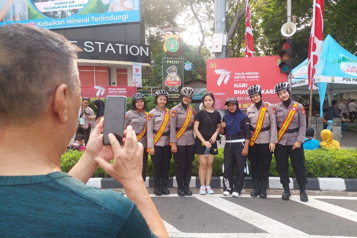 Pengunjung yang berfoto bersama dengan anggota polisi saat hari bebas kendaraan bermotor (HBKB) aliar car free day (CFD) Sudirman-Thamrin pada Minggu (2/7/2023).