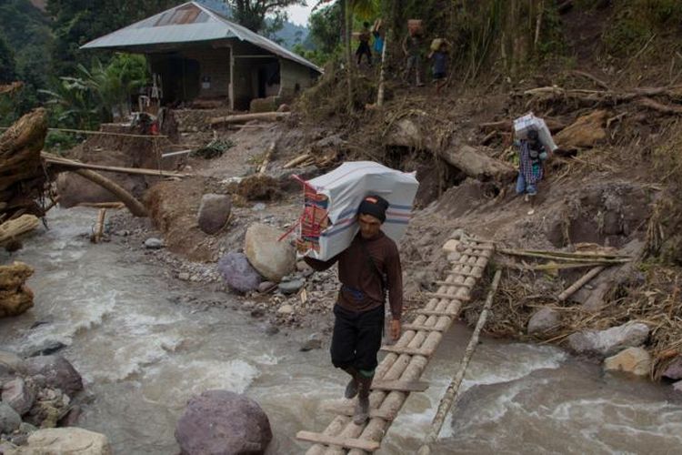 Warga memanggul karung berisi bantuan untuk korban banjir bandang dan longsor di Langgai, Gantiang Mudiak Utara Surantiah, Kecamatan Sutera, Pesisir Selatan, Sumatera Barat, Selasa (12/3/2024)