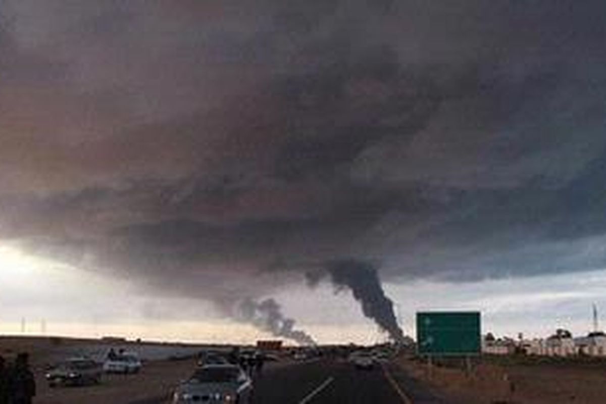 Asap dari ladang minyak yang terbakar akibat digempur pasukan pro Khadafy membubung ke langit di Ras Lanuf.