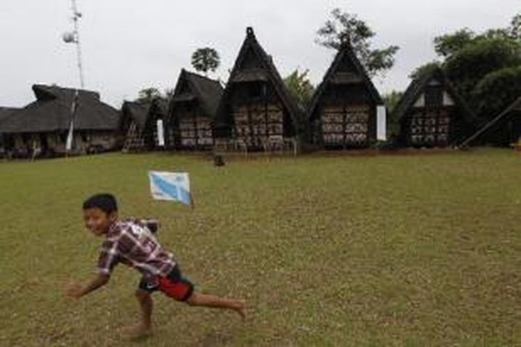 Bocah bermain layang-layang di depan lumbung padi di Kampung Budaya Sindang Barang, Desa Pasir Eurih, Kecamatan Taman Sari, Kabupaten Bogor, Rabu (19/1/2011).  