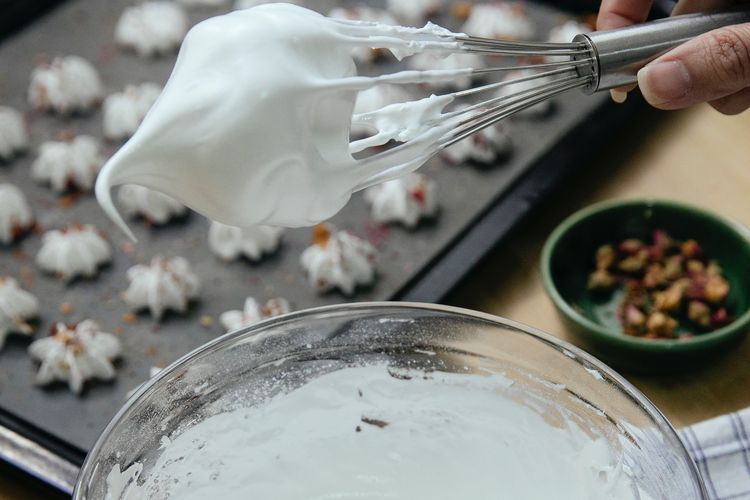 Ilustrasi proses mengocok putih telur menggunakan whisk. 