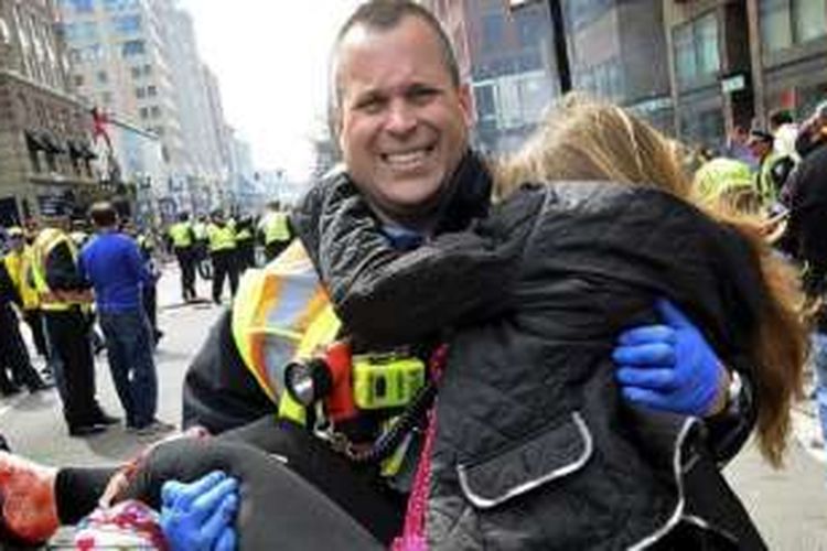 Petugas pemadam kebakaran Jimmy Proude menggendong Victoria McGrath yang terluka akibat serpihan bom di garis finis ajang maraton Boston tiga tahun lalu.