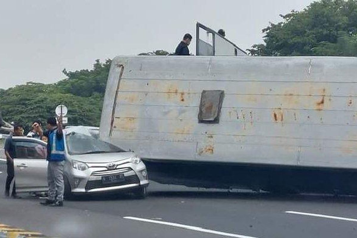 Mobil Toyota Cayla berwarna silver bernopol N-1534-BS milik pemudik tertimpa bodi bus angkutan yang terguling hingga ringsek pada kabin sisi kirinya, di Tol Surabaya-Gempol KM 756.200, Rabu (19/4/2023) siang.  