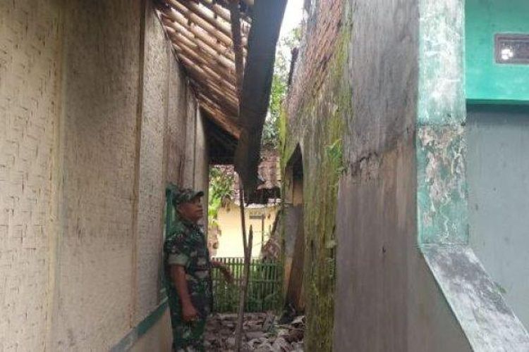 Babinsa Desa Kadupandak, Kabupaten Cianjur, Nanang, menunjukkan genting dan tembokan rumah tua yang jatuh menimpa dinding rumah tetangga dan mengagetkan warga, Sabtu (3/12/2022) sore. 