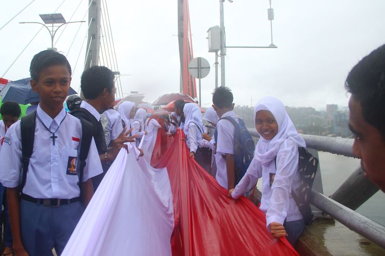 Anak-anak sekolah lintas agama ikut menjahit Bendera Merah Putih di atas Jembatan Merah Putih, Ambon, pada 19 Agustus 2017.