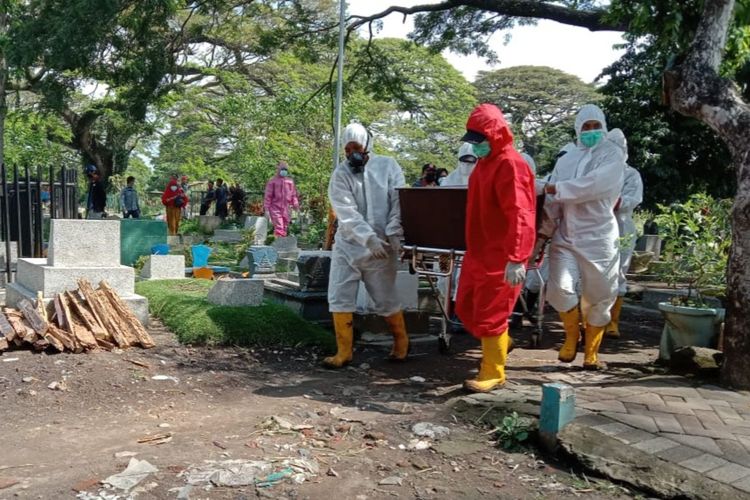 Petugas pemakaman dengan APD lengkap saat memakamkan jenazah Covid-19 di Kota Malang.