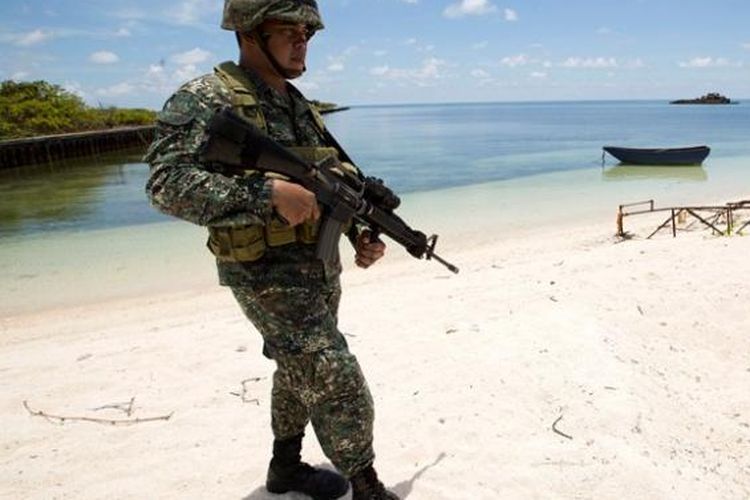 Seorang prajurit Filipina berjaga di pantai Pulau Pagasa di gugusan Kepulauan Spratly di Laut China Selatan yang disengketakan.