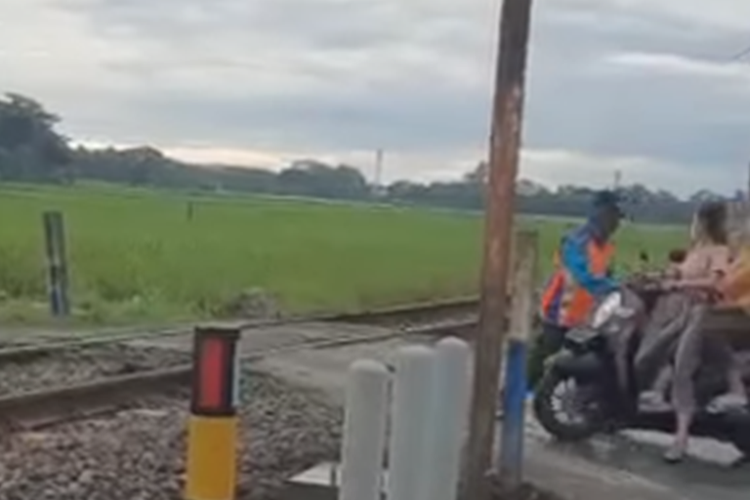 Tangkapan layar video viral yang menampilkan aksi heroik seorang petugas penjaga perlintasan kereta api (KA) tanpa palang usai menghentikan pengendara motor yang diduga hendak menerobos perlintasan.