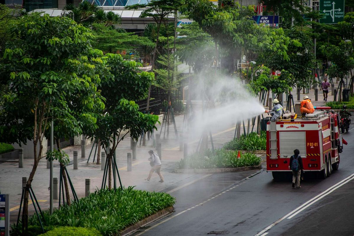 Petugas Damkar menyemprotkan cairan disinfektan di kawasan Jalan Sudirman, Jakarta, Minggu (22/3/2020). Pemprov DKI Jakarta melakukan penyemprotan fasilitas umum menggunakan cairan disinfektan di lima wilayah DKI Jakarta untuk mencegah penyebaran virus Corona atau COVID-19.