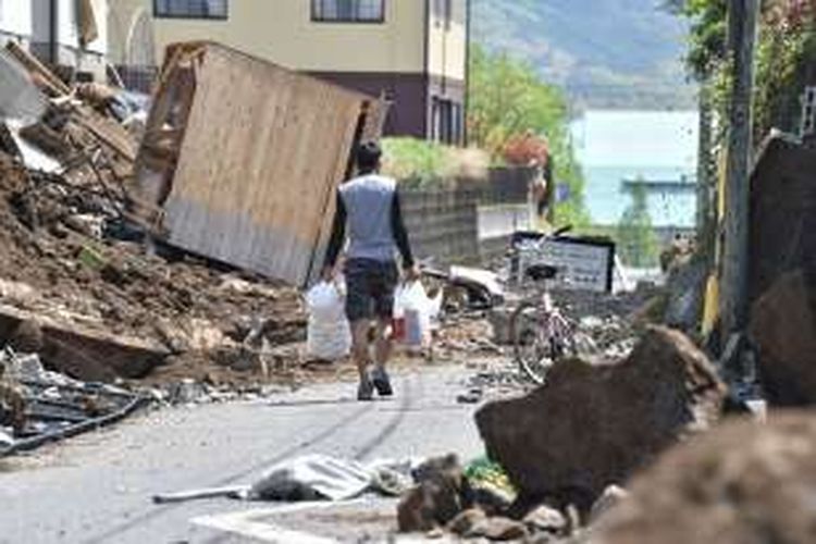 Seorang pria berjalan di antara reuntuhan bangunan akibat gempa berkekuatan 6,5 SR yang menghantam prefektur Kumamoto, Pulau Kyushu, Jepang.