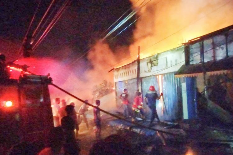 Petugas dan warga saat berupaya memadamkan api kebakaran belasan ruko pasar di Kelurahan Ujungbatu, Kecamatan Ujungbatu, Kabupaten Rokan Hulu, Riau, Jumat (12/4/2024) malam.