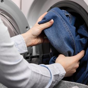Ilustrasi mencuci celana jeans di mesin cuci. 