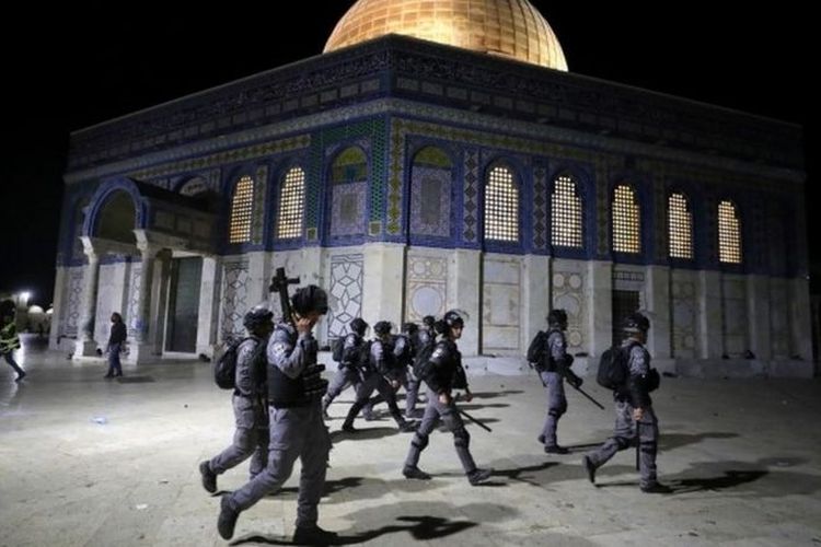 Polisi Israel berjalan melewai tempat suci Dome of the Rock saat bentrokan dengan warga Palestina.