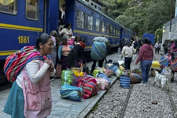 Penduduk setempat yang membawa tas-tas hasil bumi menunggu di samping layanan kereta Machu Picchu yang dilanjutkan setelah hampir tiga minggu penangguhan karena protes di Peru.