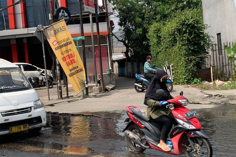 Kondisi Jalan Raya Ceger, Pondok Aren, Tangerang Selatan, Rabu (3/5/2023) siang. Genangan air comberan meluap ke jalan membuat pengendara motor naik ke atas trotoar untuk menghindari genagan air berbau busuk tersebut. Terlihat banner di sisi jalan sebagai bentuk protes warga sekitar.