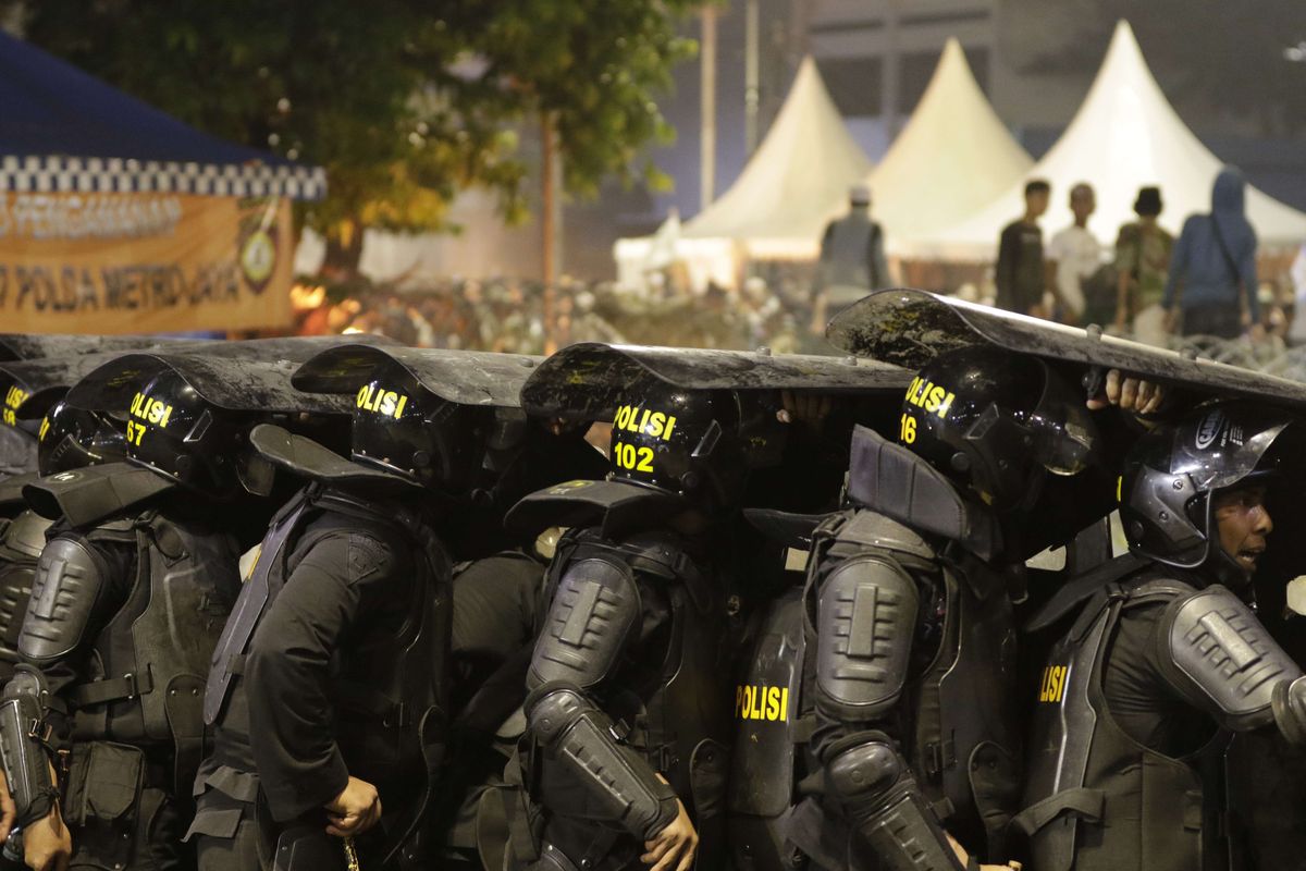 Polisi bertahan dari lemparan batu para demonstran yang ricuh di dekat gedung Bawaslu, Jalan MH Thamrin, Rabu (22/5/2019).