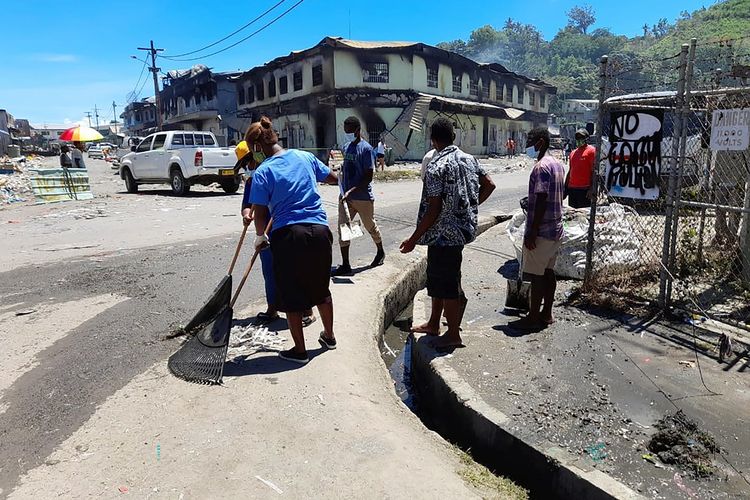 Warga Kepulauan Solomon membersihkan puing-puing sisa kerusuhan di Pecinan ibu kota Honiara, Minggu (28/11/2021), saat situasi mereda usai kericuhan berhari-hari yang membuat setidaknya tiga orang tewas.