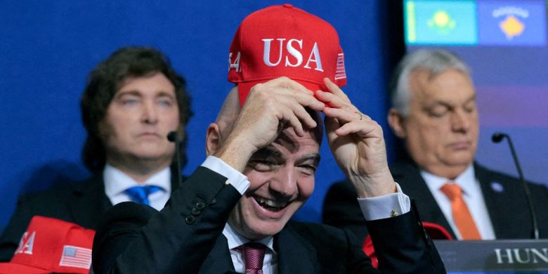 Presiden FIFA Gianni Infantino mengangkat topi Amerika Serikat saat menghadiri pertemuan perdana Dewan Perdamaian di Institut Perdamaian pada 19 Februari 2026 di Washington, DC.