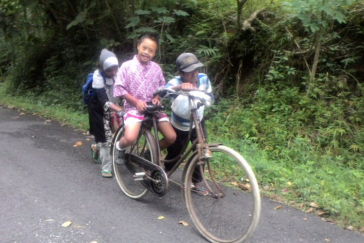 Hernowo mengendalikan kemudi sepeda, Kamilah mendorongnya, saat mendaki bukit. Wahyu tetap duduk di boncengan. Seperti inilah setiap hari Hernowo membawa Wahyu sekolah yang jauhnya belasan kilometer. Hernowo yang setengah tuli sejak lahir tidak menyerah menyekolahkan anaknya yang down syndrome. Di usia senja mereka, ia mengharapkan Wahyu bisa cepat mandiri.