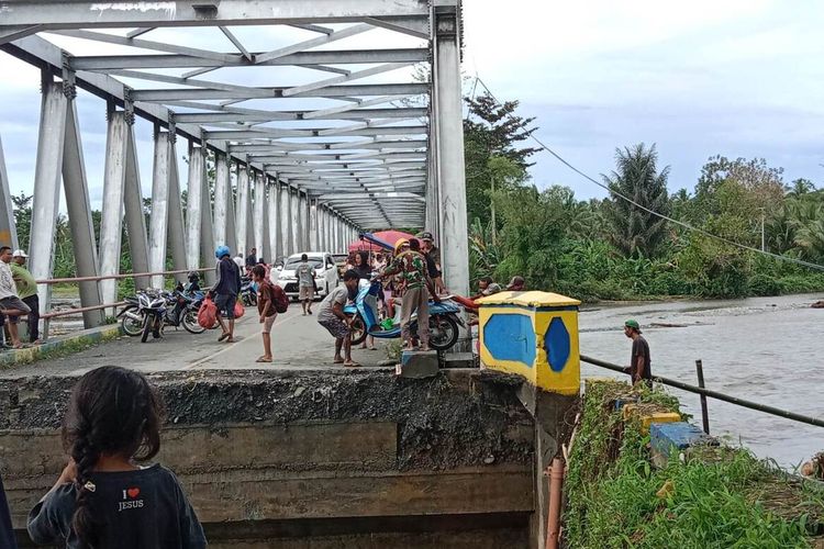 Sejumlah warga membantu menurunkan sepeda motor yang hendak melintas di jembatan darurat di Kali Mala di kecamatan Elpaputih, Kabupaten Seram Bagian Barat, Maluku, Rabu (20/7/2022)