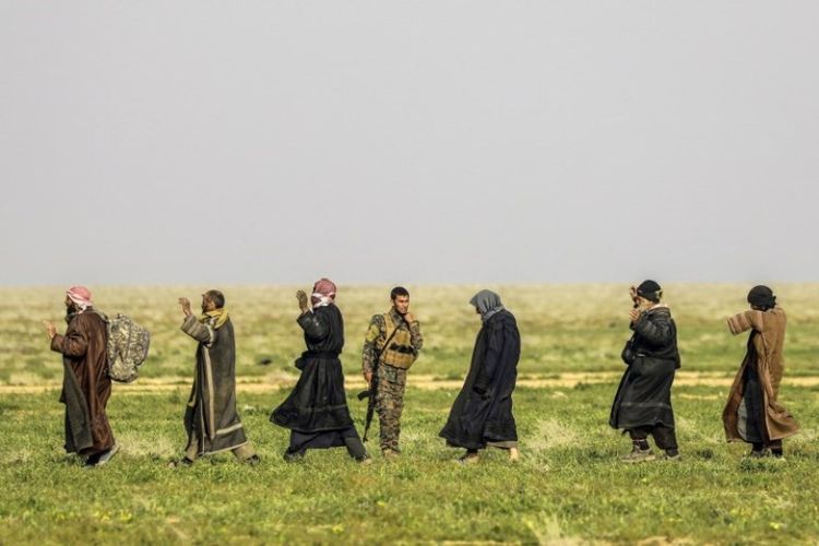 Seorang tentara Pasukan Demokratik Suriah (SDF) yang didukung AS berdiri mengawasi orang-orang yang mengantre di area pemeriksaan setelah dievakuasi dari desa Baghouz,  provinsi Deir Ezzor di Suriah, yang dikuasai ISIS, Selasa (26/2/2019). (AFP/DELIL SOULEIMAN)