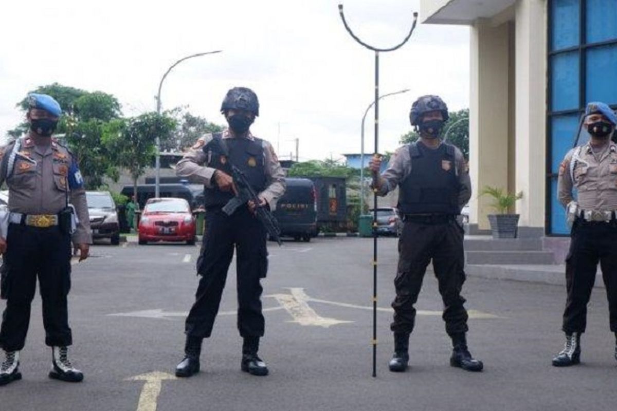 Sejumlah anggota polisi bersenjata lengkap berjaga-jaga di pintu utama kantor Polres Metro Jakarta Pusat, Kamis (1/4/2021). 
