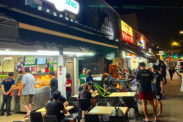 Pembeli sedang mengantri di depan Rumah Makan Fong Seng, Pasir Panjang, Singapura Barat, Rabu malam (29/3/2023). Mayoritas warga Singapura memilih tidak memakai masker lagi setelah berakhirnya status siaga pandemi Covid-19 pada bulan Februari 2023.
