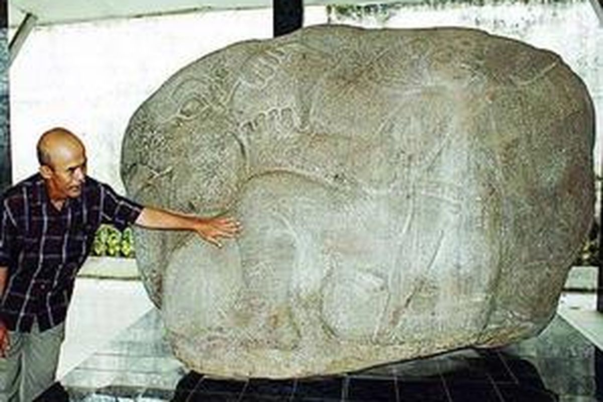 Nurhadi Rangkuti meraba-raba batu gajah sambil menjelaskan torehan gelang kaki pada wujud tokoh manusia yang memegang gajah, yang merupakan benda koleksi Museum Balaputradewa di Palembang.