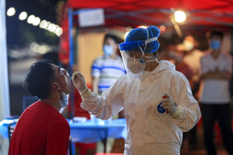 Seorang pekerja medis mengambil sampel swab dari seorang penduduk selama putaran tes Covid-19 massal di Wuhan di provinsi Hubei, China tengah, pada 5 Agustus 2021. 