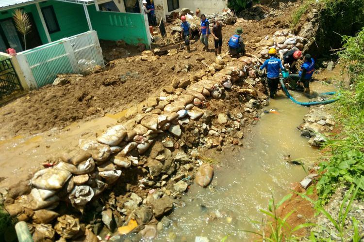 Petugas tengah berupaya membangun tanggul yang diperkuat kawat bronjong untum menambal sementara tanggul yang jebol akibat gerusan air sungai kecil di sekitar Komplek Jatiendah Regency.