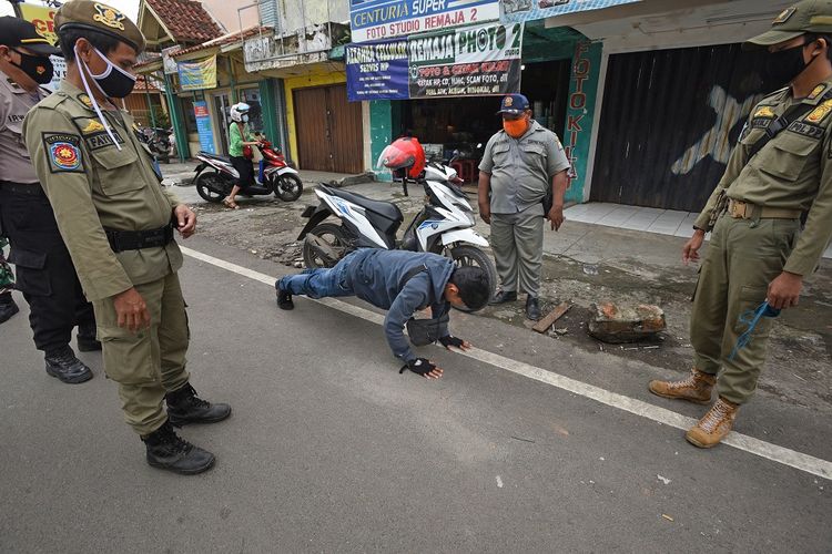 Personel gabungan Polri dan Satuan Polisi Pamong Praja memberi hukuman kepada warga yang terjaring Operasi Pendisiplinan Protokol Kesehatan di Pasar Induk Rau, Serang, Banten, Rabu (13/1/2021). Operasi tersebut digelar untuk mendisiplinkan warga dalam mematuhi ketentuan protokol kesehatan selama Pemberlakuan Pembatasan Kegiatan Masyarakat (PPKM) tanggal 11-25 Januari 2021 guna menekan penyebaran COVID-19. ANTARA FOTO/Asep Fathulrahman/wsj.