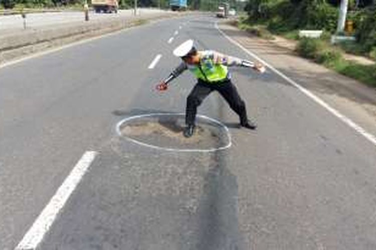 Salah seorang anggota Satlantas Polres Batang, Jawa Tengah, mendandai jalan berlubang di Jalur Pantura, Rabu (26/10/2016)