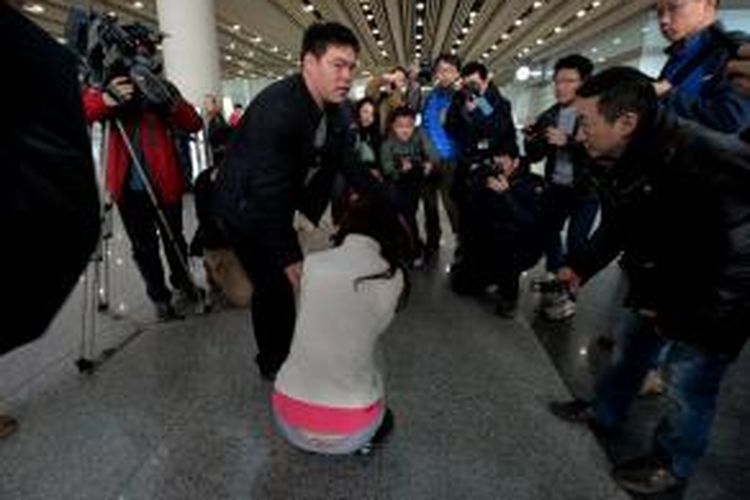 Seorang wanita yang diduga keluarga penumpang Malaysia Airlines MH370 terduduk dan menangis di Beijing Airport setelah mendengar berita tentang hilangnya pesawat Boeing 777-200 milik Malaysia Airlines, Sabtu (8/3/2014). 