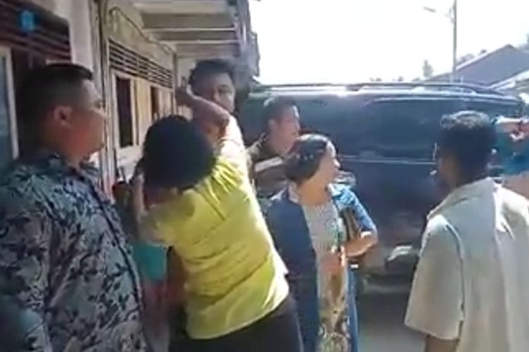 seorang ibu berusaha melindungi mantan Bupati Nias Selatan Idealisman Dachi, usai terjadi pelemparan dengan kotoran babi yang hampir mengenai dirinya, saat menghadiri acar syukuran atas pemenangan Kepala Desa Hilisatoro Gewa, atas nama Wisnu Duha, Kecamatan Toma, Kabupaten Nias Selatan, Sumatera Utara, Sabtu (25/1/2020) siang.