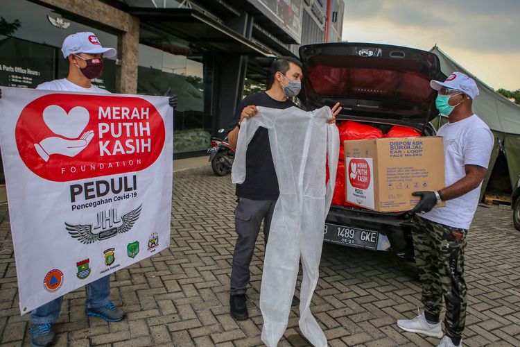 Koordinator Distribusi Posko Merah Putih Kasih Foundation JHL Group Marcelinus Enggala (kanan) menyerahkan bantuan kepada perwakilan Pewarta Foto Indonesia (PFI) Hendra Eka (tengah) di Tangerang, Banten, Minggu (3/5/2020). Merah Putih Kasih Foundation memberikan donasi Alat Pelindung Diri (APD) dan masker kepada jurnalis foto sebagai bentuk kepedulian dan upaya pencegahan penyebaran wabah COVID-19.