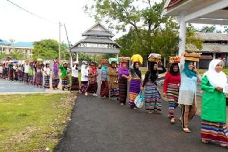 Para wanita terlihat menjinjing barang sembako di atas kepala masing-masing. Para wanita keturunan Flores, NTT, ini tengah melaksanakan adat Panlala di Pulau Buton, Sulawesi Tenggara, Kamis (21/1/2016).