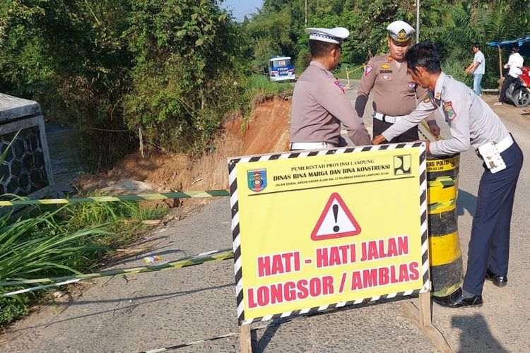 Polisi memasang papan peringatan di lokasi jalan ambles di jalan lintas kecamatan di Lampung Tengah, Senin (15/5/2023).
