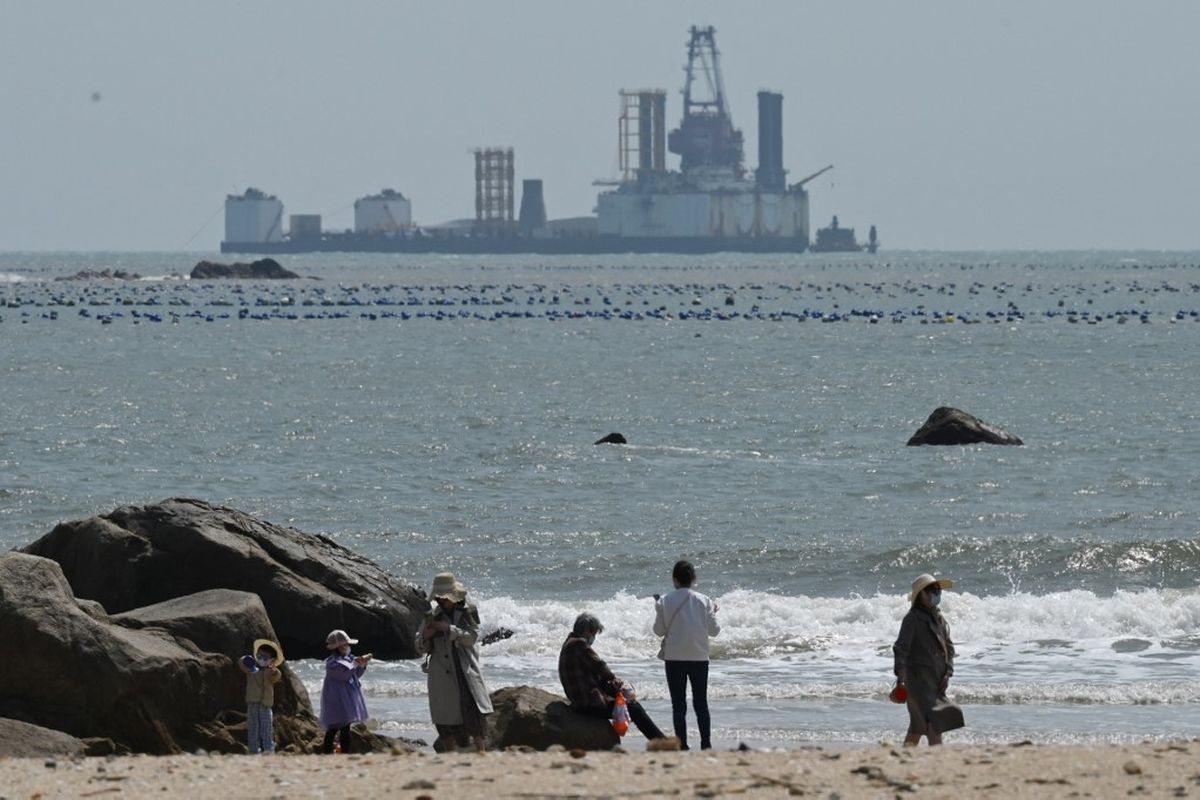 Orang-orang berjalan di pantai di pulau Pingtan, di seberang Taiwan, di provinsi Fujian tenggara China pada 9 April 2023. China melakukan latihan militer hari kedua di sekitar Taiwan pada 9 April, yang disebutnya sebagai peringatan keras kepada pemerintah pulau yang memerintah sendiri setelah pertemuan antara presidennya dan ketua DPR AS.