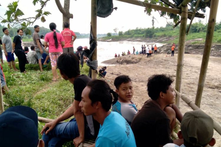 Puluhan warga petugas kepolisian dan BPBD berkumpul di sekitar lokasi terjatuhnya Bagas ke aliran Sungai Brantas di Desa Mronjo, Kecamatan Selopuro, Kabupaten Blitar, Rabu (23/3/2022)