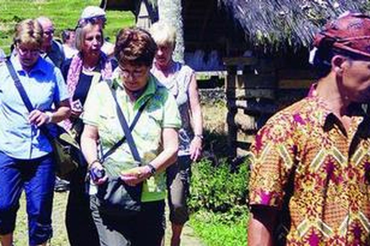 Sejumlah turis Jerman diantar pemandu wisata berpakaian khas adat Naga berjalan-jalan di Kampung Adat Naga awal Mei 2012.