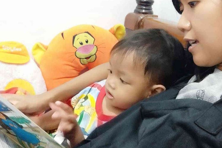 Kebiasaan membacakan buku cerita pada anak sebelum tidur.
