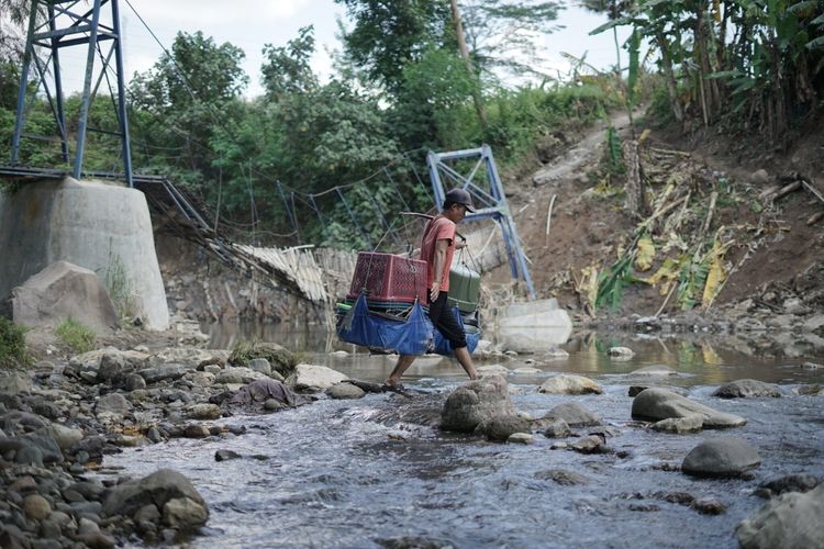 Sejumlah warga terpaksa menyeberangi sungai untuk beraktivitas akibat terputusnya akses jembatan di Bantargadung, Sukabumi, Jawa Barat, beberapa waktu lalu.
