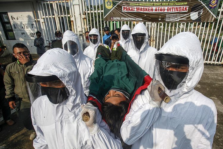 Petugas Satpol PP Kabupaten Bogor menggunakan pakaian hazmat membawa seorang pelanggar PSBB pra Adaptasi Kebiasaan Baru (AKB) dengan tandu menuju pemakaman di kawasan Stadion Pakansari, Kabupaten Bogor, Jawa Barat, Minggu (6/9/2020). Pemerintah Kabupaten Bogor menerapkan sanksi denda sebesar Rp100 ribu serta sanksi sosial yakni kewajiban membersihkan area makam, push up dan  tahapan prosesi pemakaman COVID-19, hal tersebut untuk memberikan efek jera bagi warga yang tidak menggunakan masker di tempat umum.