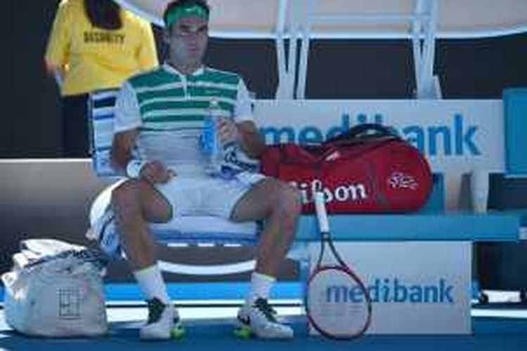 Roger Federer beristirahat pada sela-sela pertandingan melawan Alexandr Dolgopolov, Rabu (20/1/2016). 
