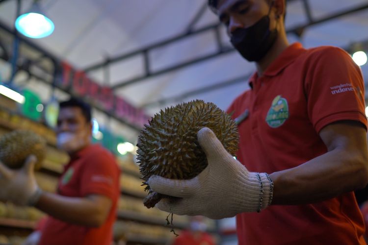 Staf Si Bolang Durian Medan tengah membelah durian untuk disajikan.
