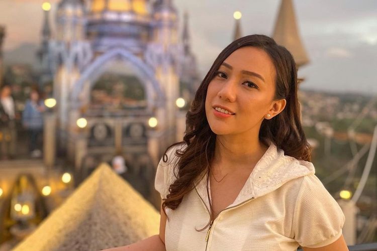 Artis Anastasya Panggabean berpose dengan latar destinasi wisata.